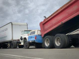 A fleet of trucks lined up outside a workshop ready for service.