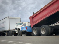 A fleet of trucks lined up outside a workshop ready for service.