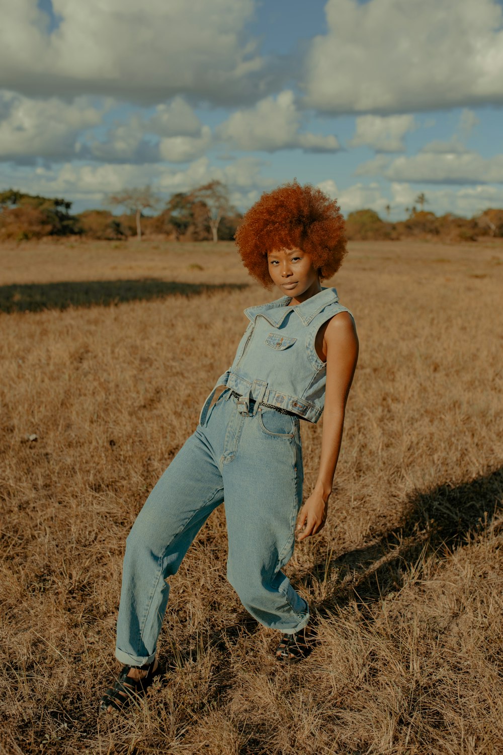 woman in blue denim vest and blue denim jeans standing on grass field