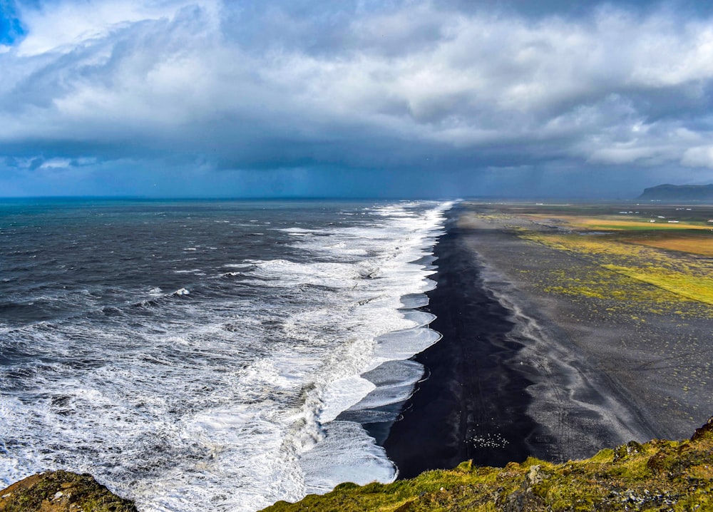 ocean waves crashing on shore under white clouds and blue sky during daytime