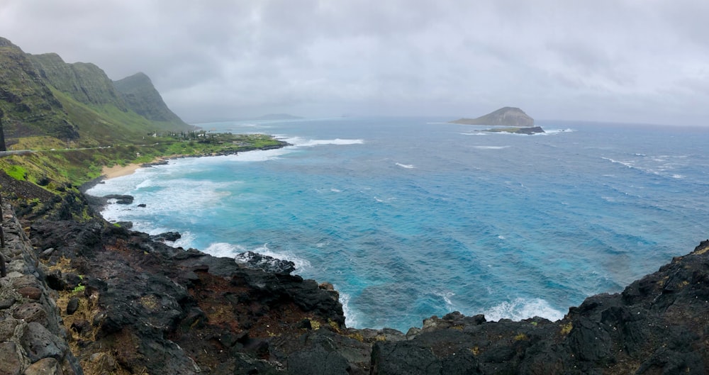 body of water near mountain under cloudy sky during daytime