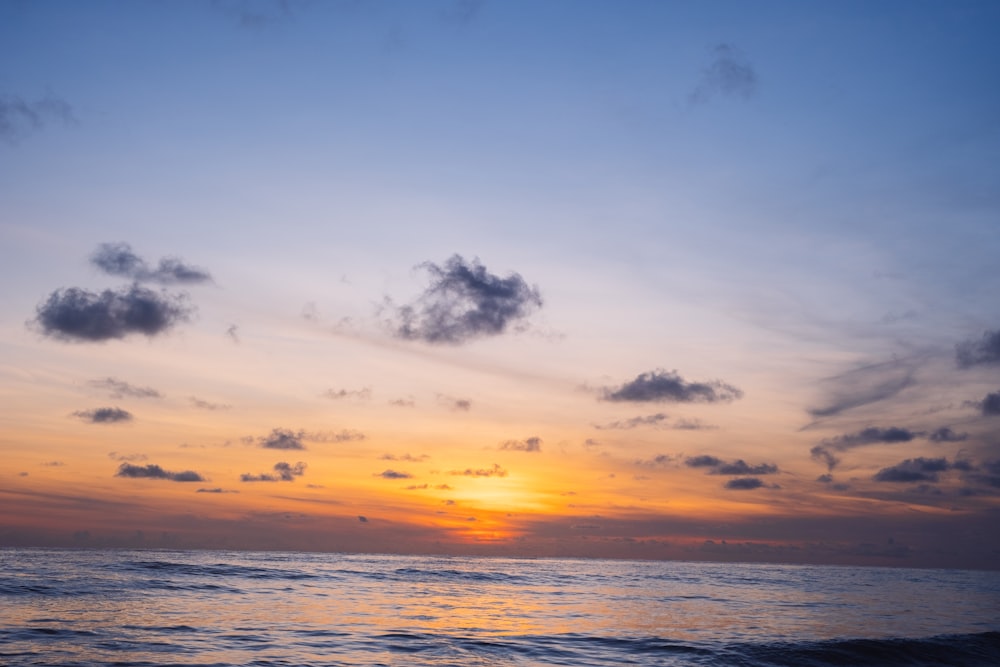 body of water under cloudy sky during sunset