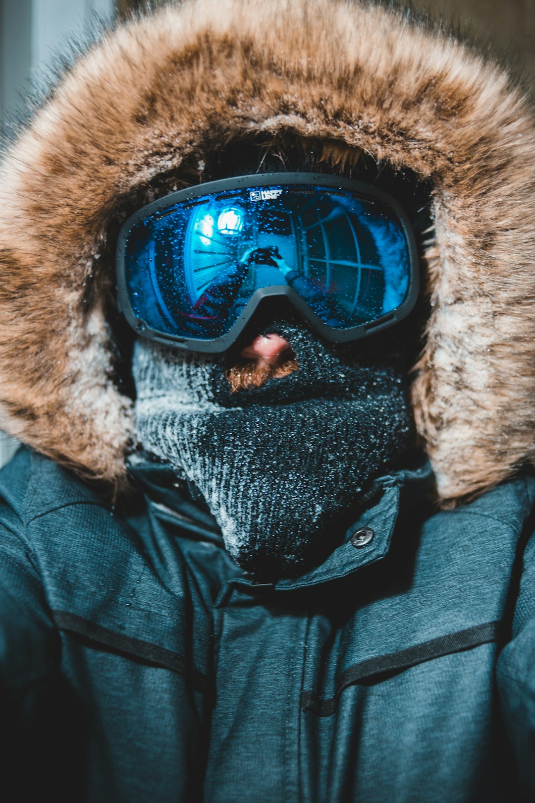 person wearing blue coat and blue snow goggles
