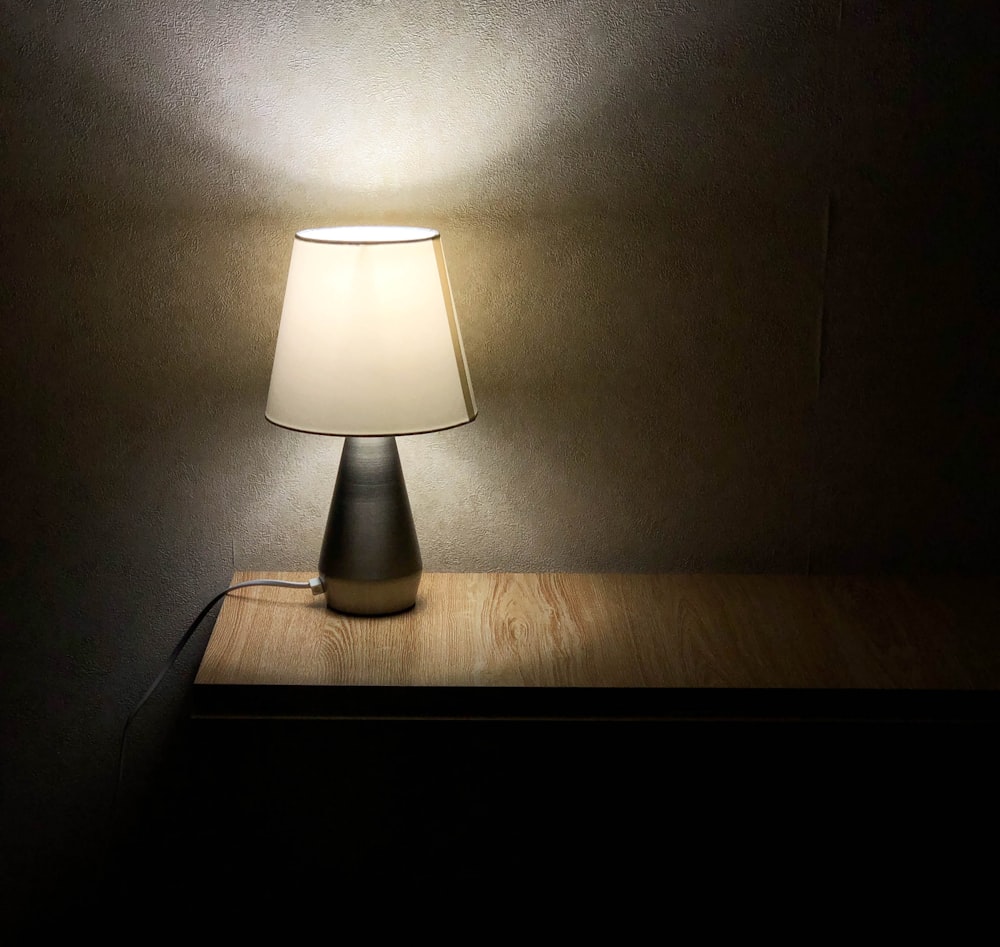 Lámpara de mesa blanca sobre mesa de madera marrón