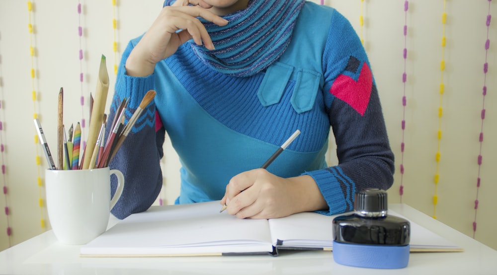 persona in camicia nera a maniche lunghe che scrive su carta bianca