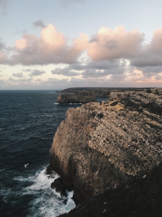 brown rock formation beside body of water during daytime in Sagres Portugal