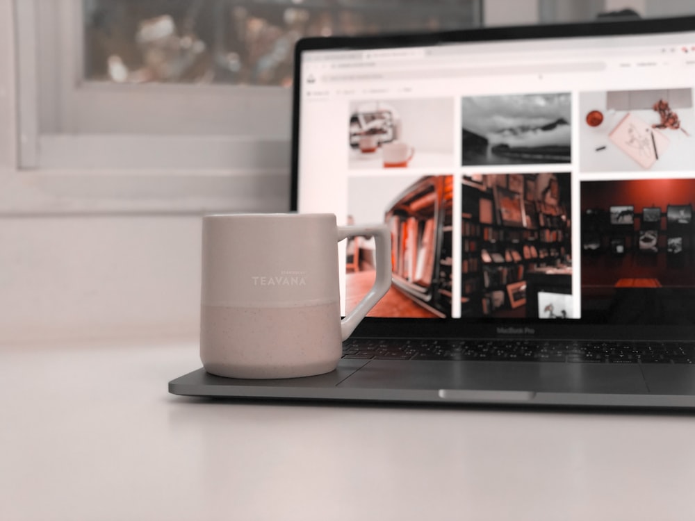 white ceramic mug beside black laptop computer