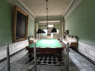 A cozy billiard club room with players focused on a French billiard table.
