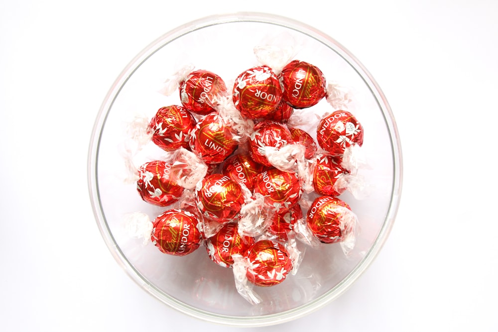 red and white round candies in clear glass bowl