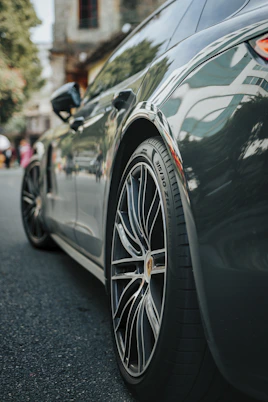 A clean, modern car parked in front of a bustling Kolhapur street market.