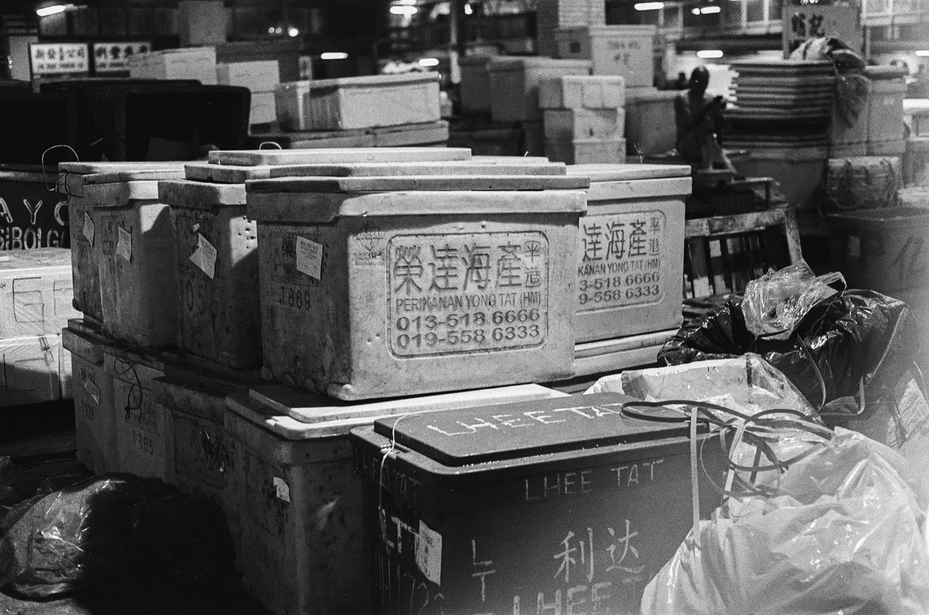 grayscale photo of a man in white shirt standing near the table