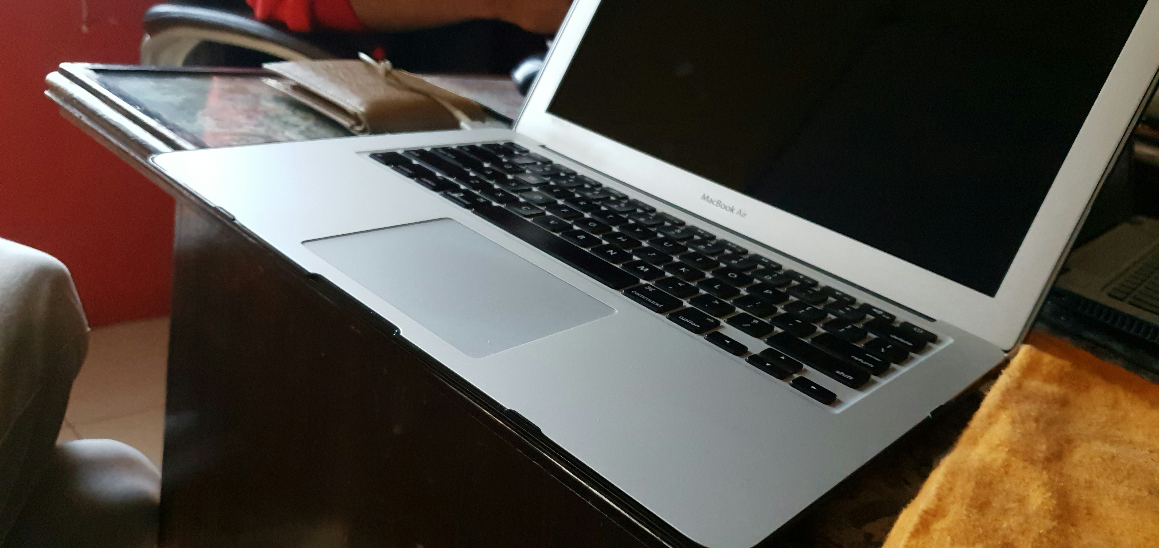 MacBook Air on wooden desk, side angle view, warm ambient light