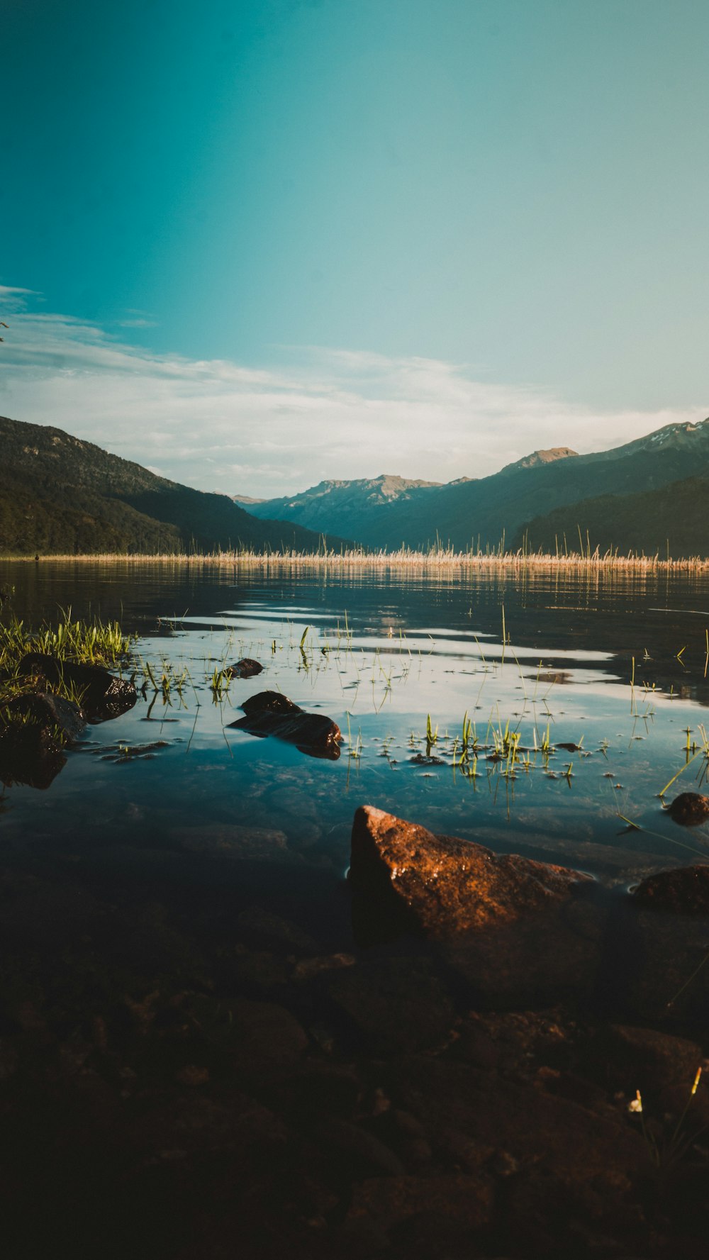 Specchio d'acqua vicino alla montagna verde sotto il cielo blu durante il giorno