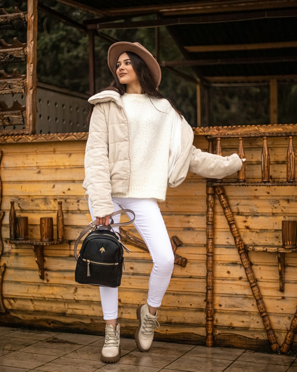 woman in white long sleeve shirt and brown pants holding black and gray backpack