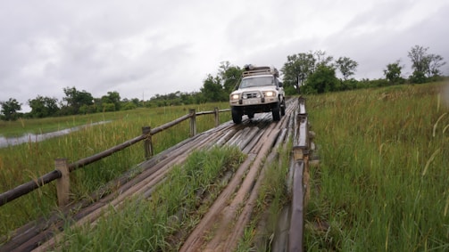 A 4x4 vehicle crossing a shallow lagoon stream under a bright blue sky.