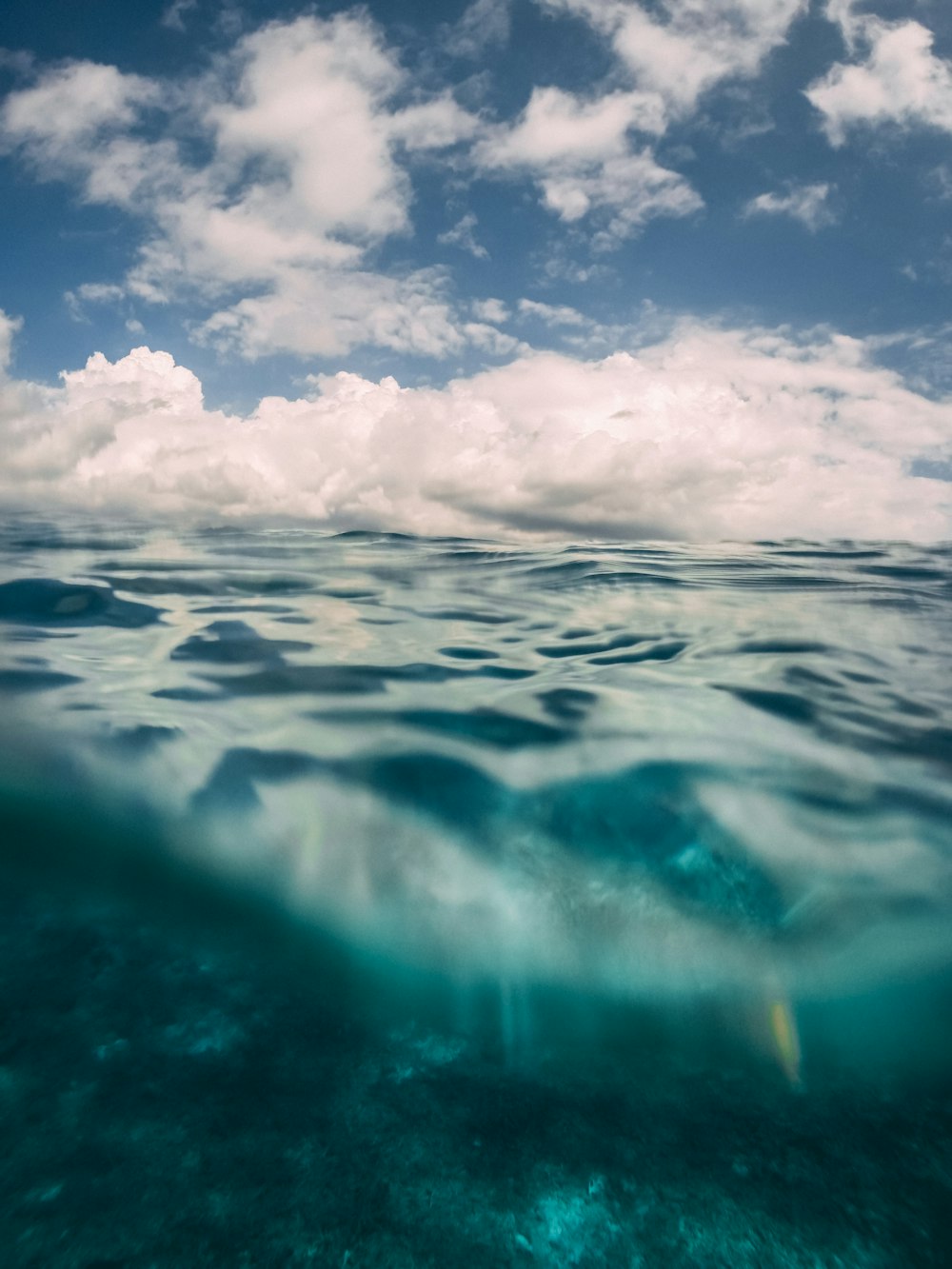 agua azul del océano bajo nubes blancas y cielo azul durante el día