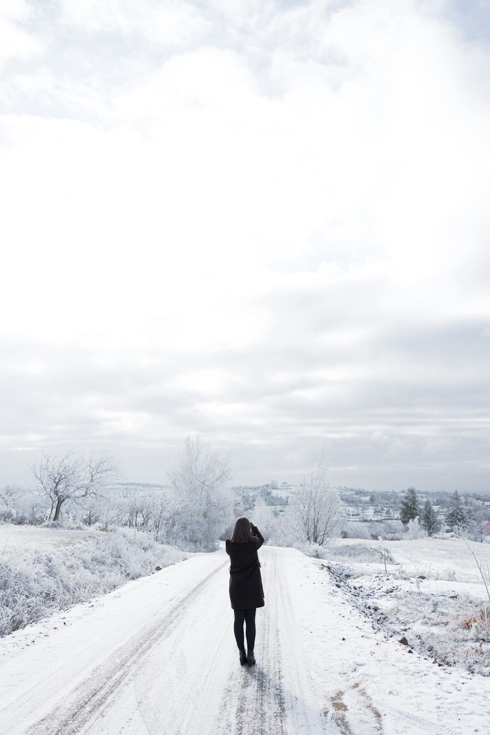 Persona con chaqueta negra de pie en el suelo cubierto de nieve durante el día