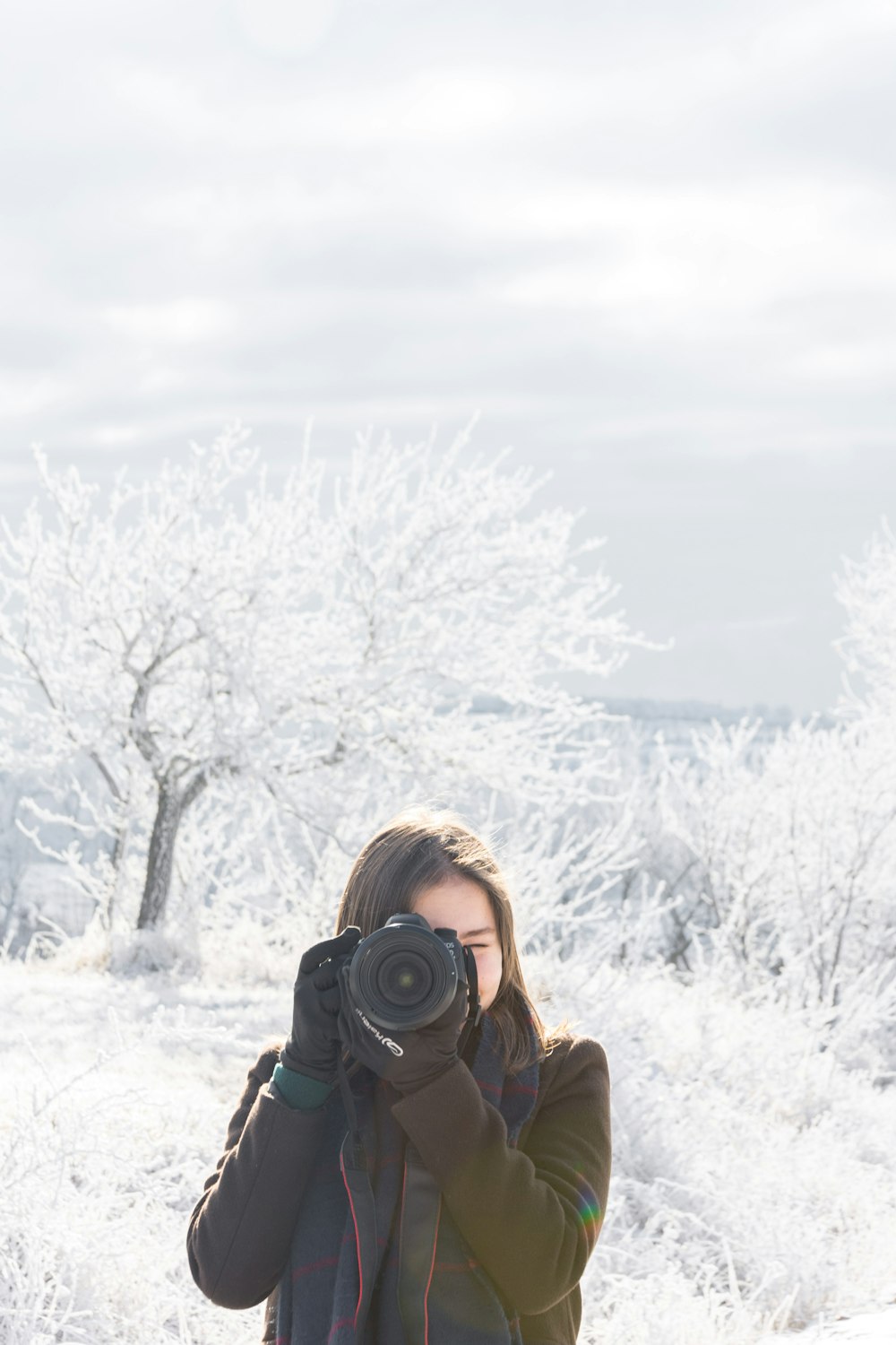 Femme en veste marron tenant un appareil photo reflex numérique noir