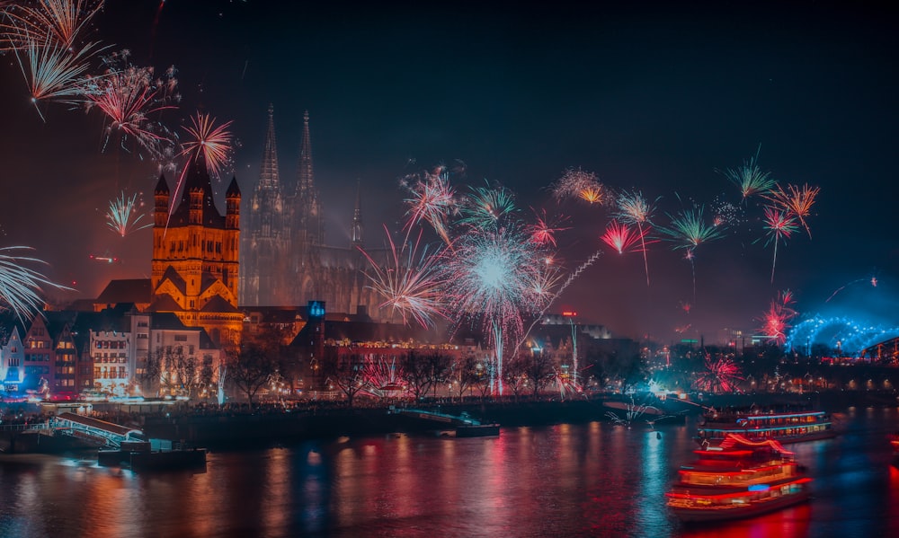 fireworks display over river near city buildings during night time