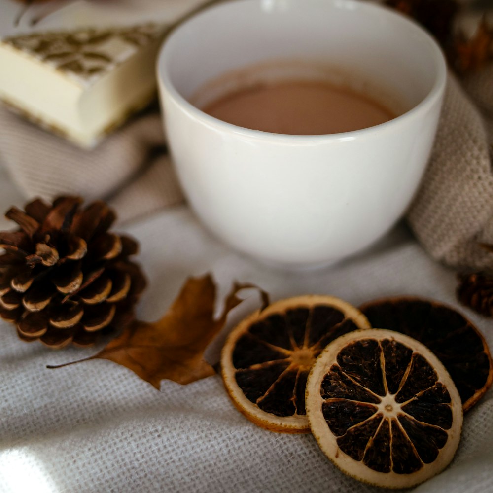 white ceramic mug with coffee beside brown leaves