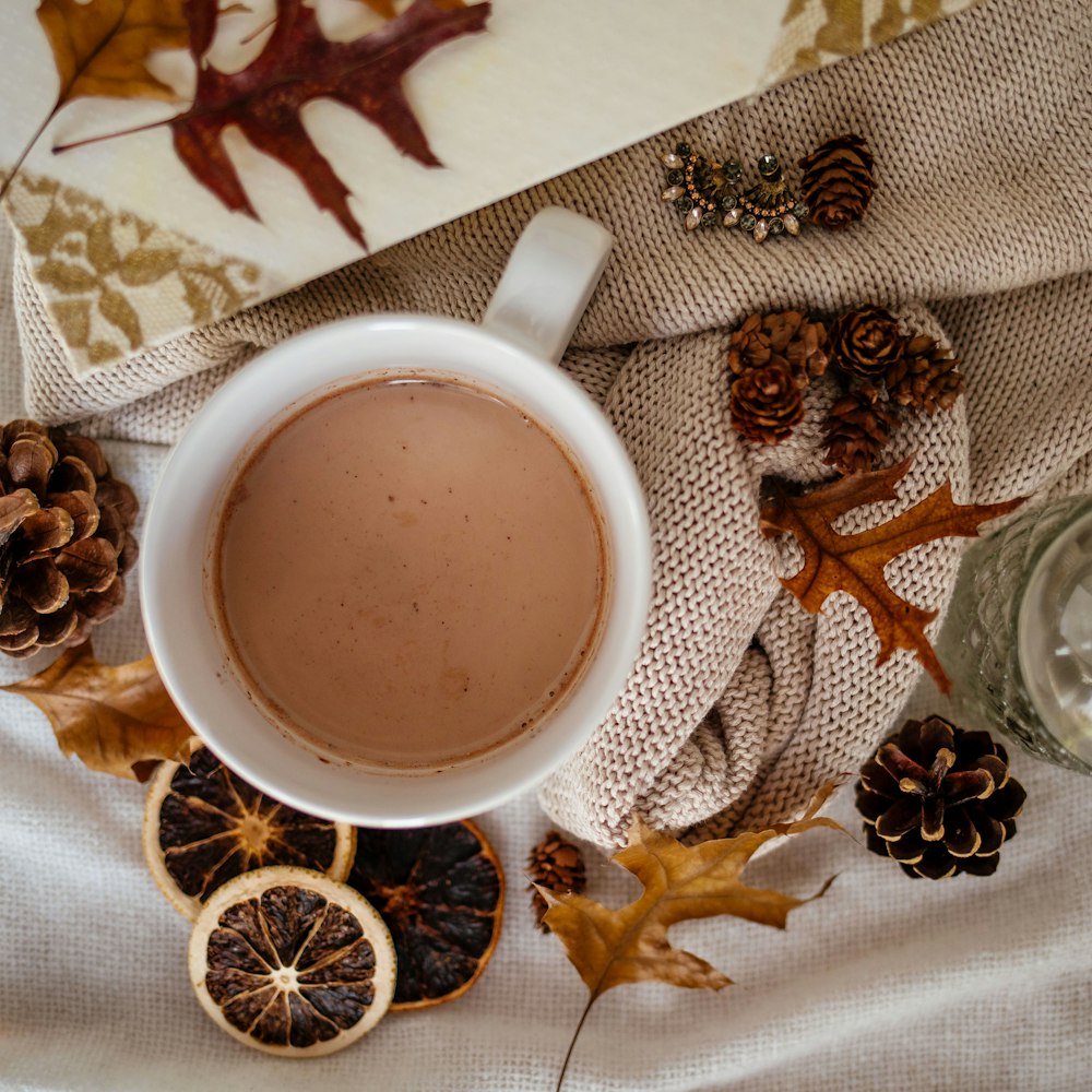 white ceramic mug with coffee on white and brown floral textile