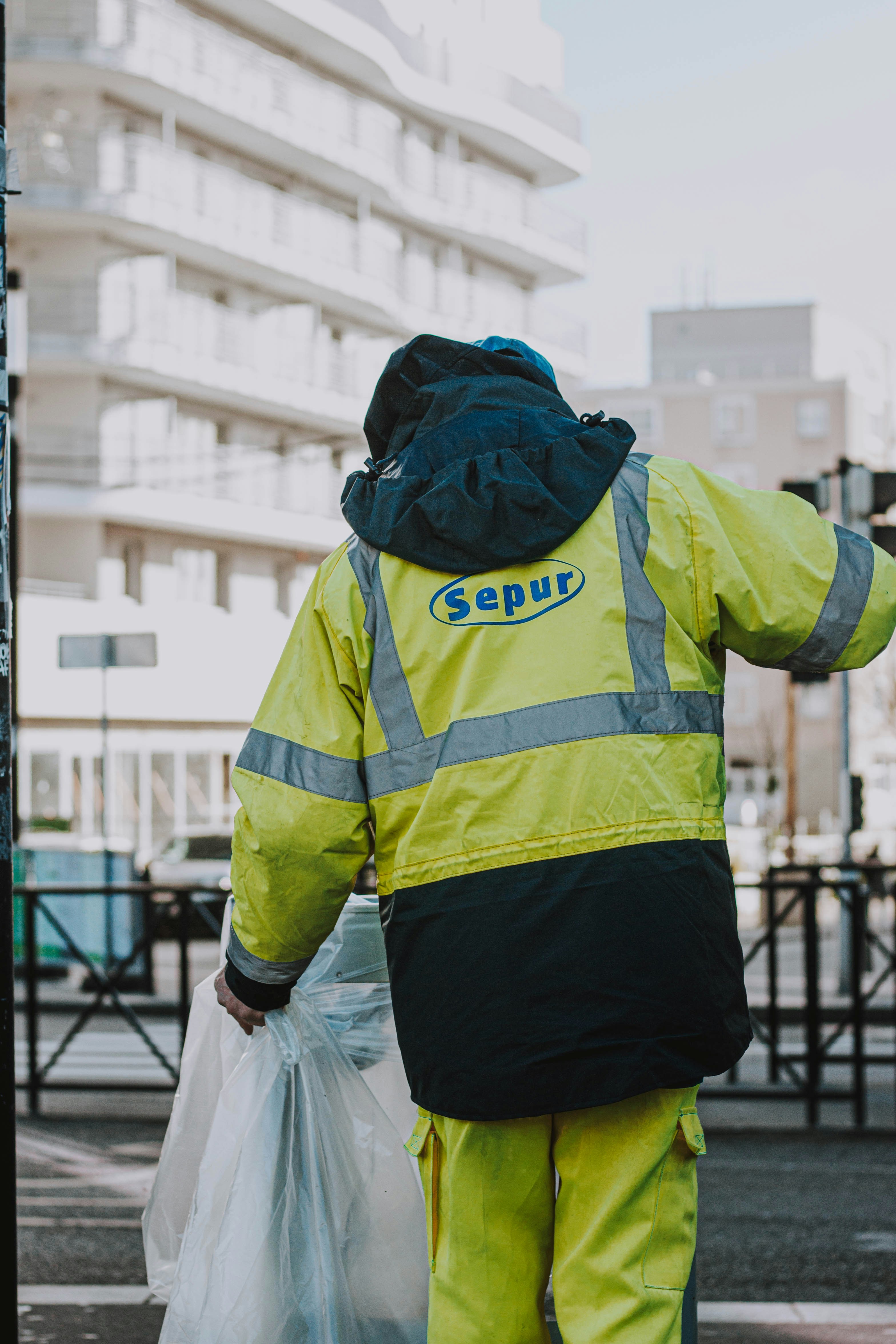 a man in a yellow jacket is walking down the street