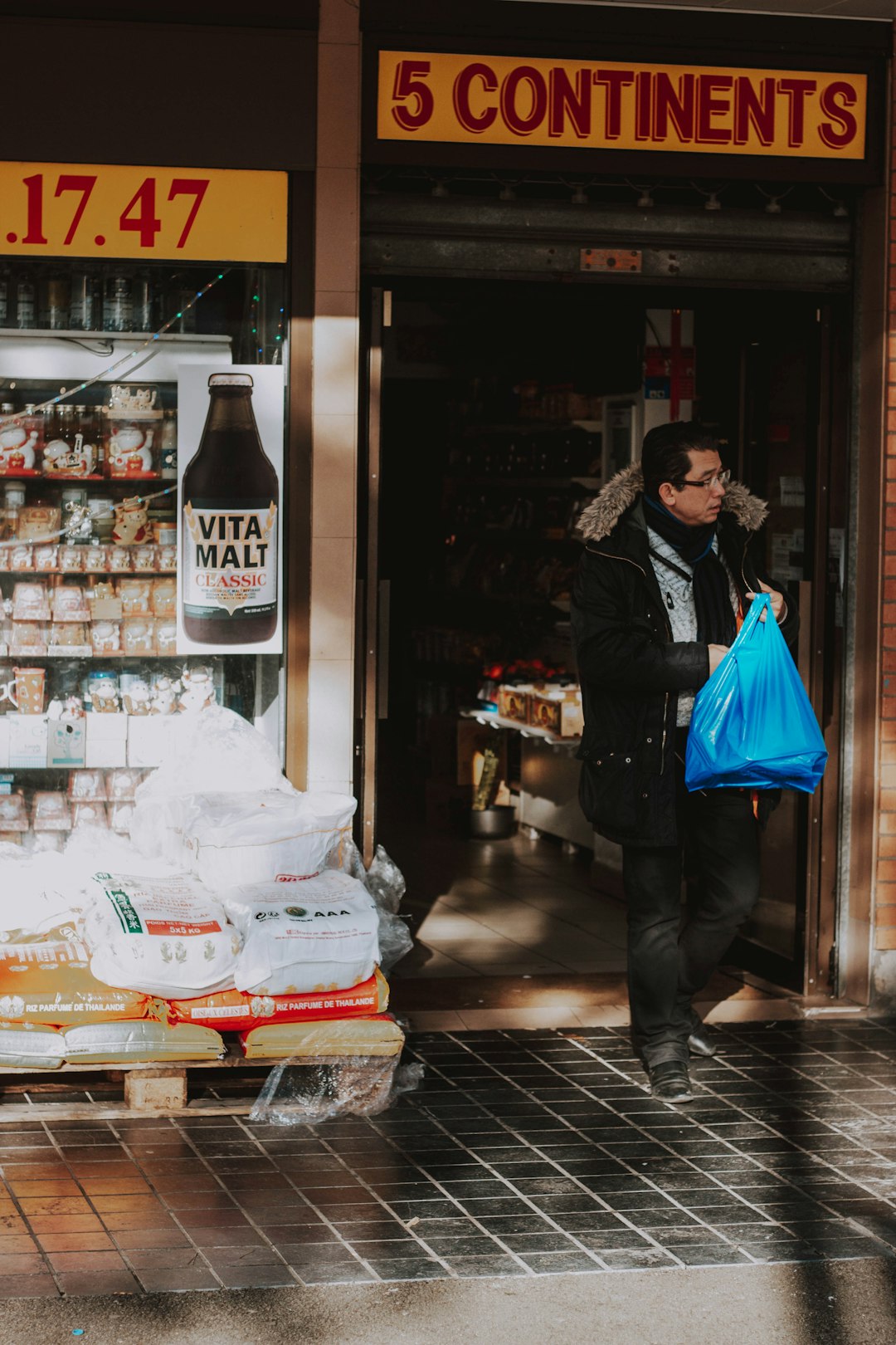 man in black jacket and blue pants standing beside store