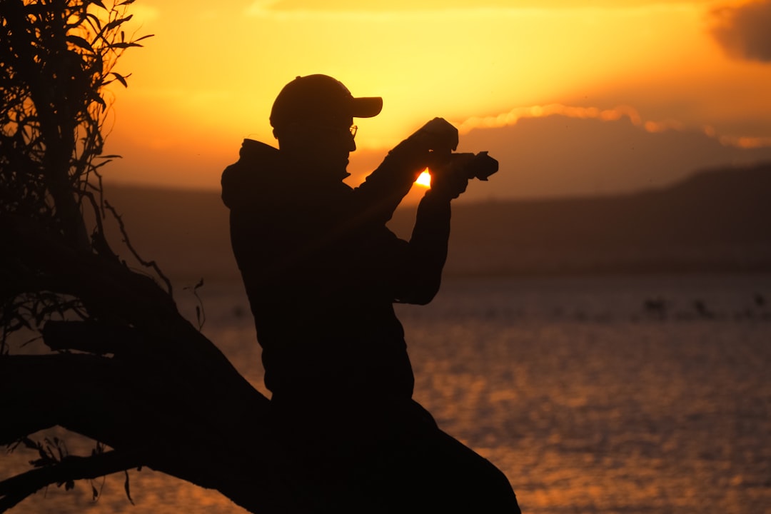 silhouette of man holding camera during sunset