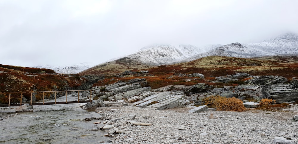 white houses on gray rocky ground near gray mountain under white cloudy sky during daytime