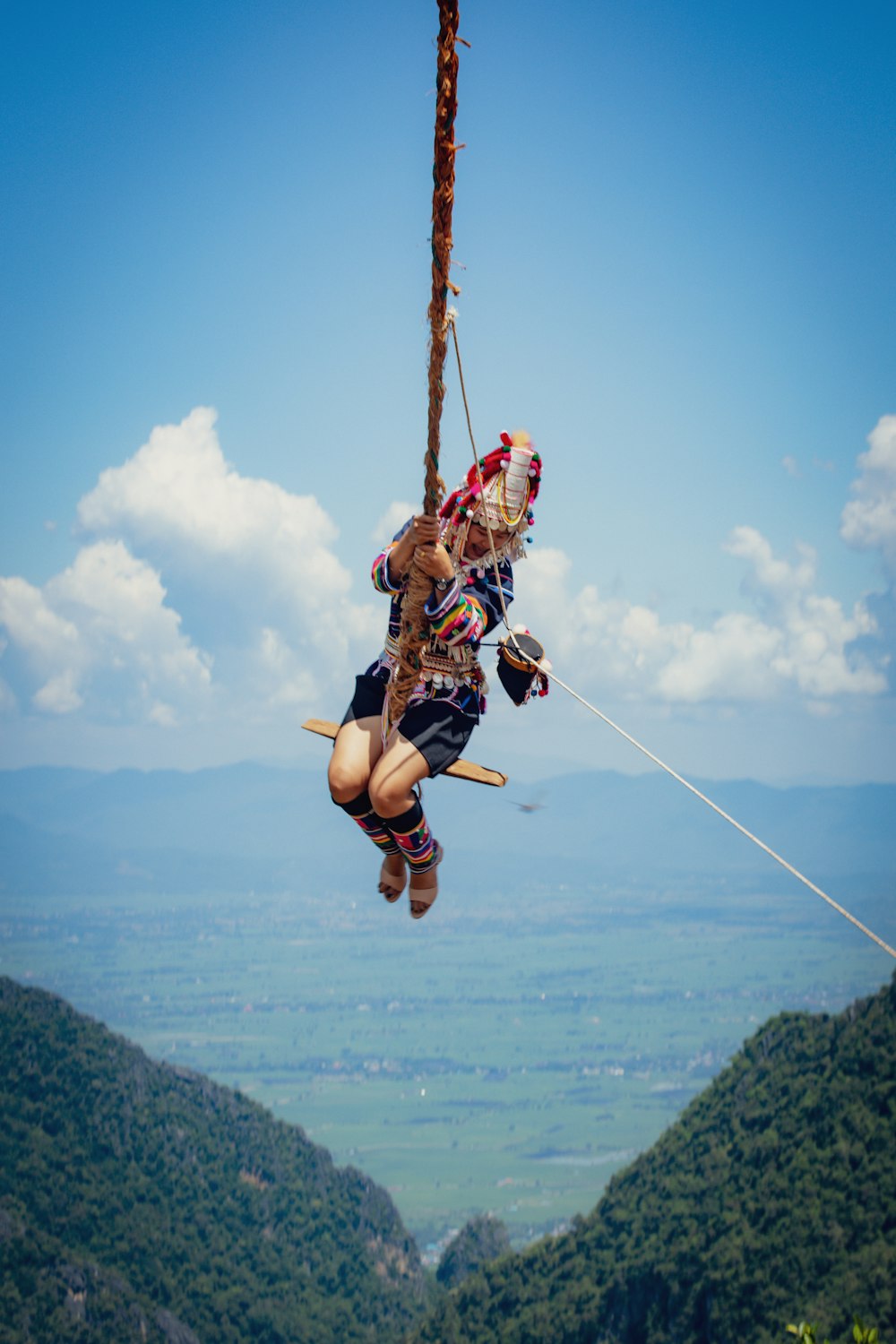 a group of people hanging from a rope on top of a mountain