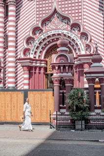 a woman in a white dress walking past a pink and white building