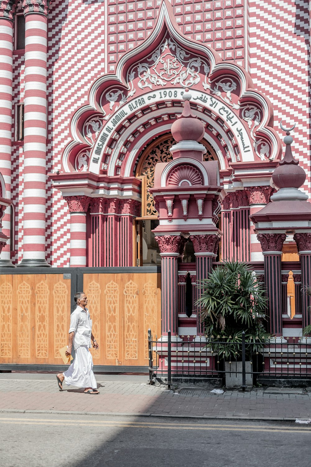 a woman in a white dress walking past a pink and white building