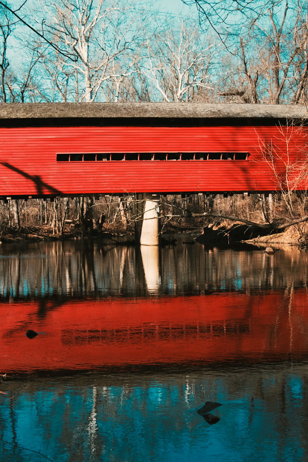 a red covered bridge over a body of water