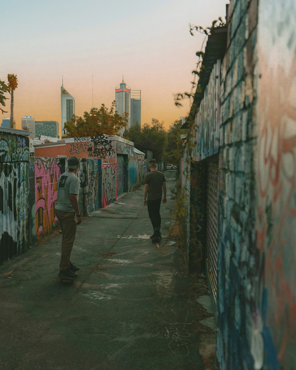 a couple of men walking down a sidewalk next to a wall