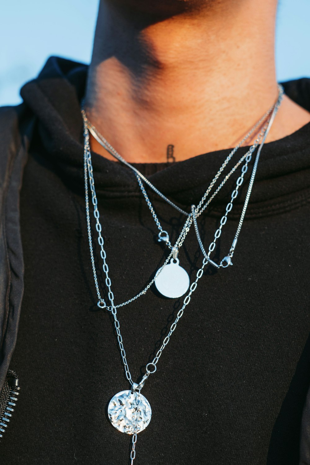 a man wearing a black shirt and a silver necklace