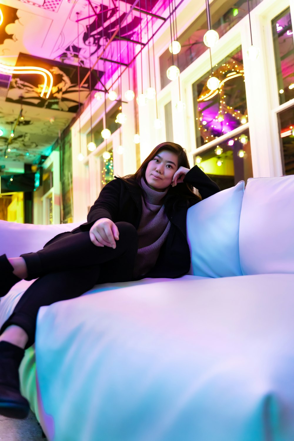 a woman sitting on top of a bed covered in pillows