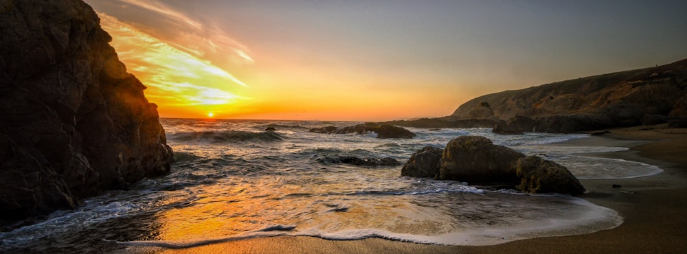 the sun is setting over the water at the beach