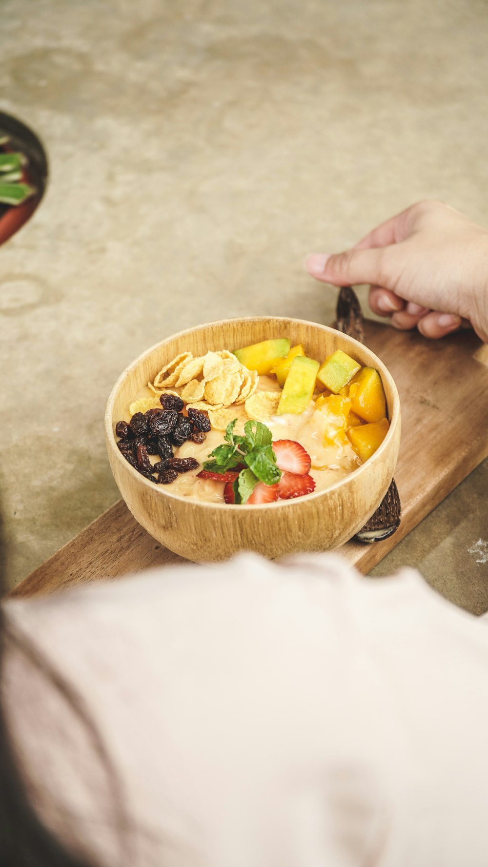 a wooden bowl filled with fruit on top of a cutting board