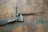 A handcrafted twisted metal knife with an ornate handle is placed on a rustic, textured wooden surface. The blade and handle show signs of artisanal craftsmanship, with intricate twists and a spiraling design.