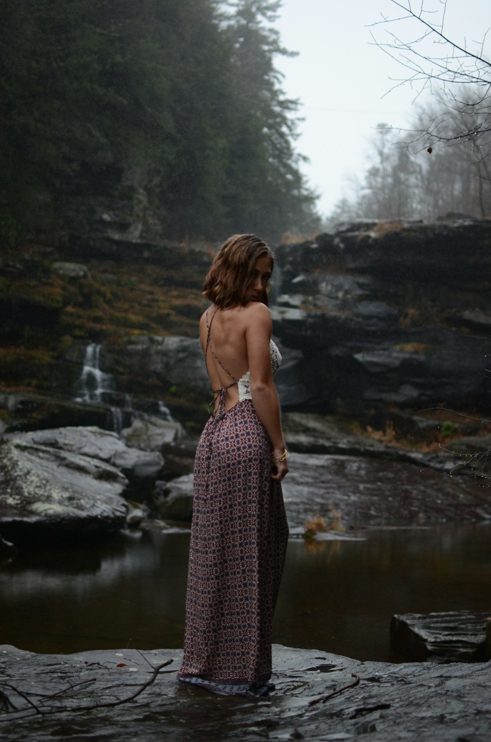 a woman in a long dress standing on a rock