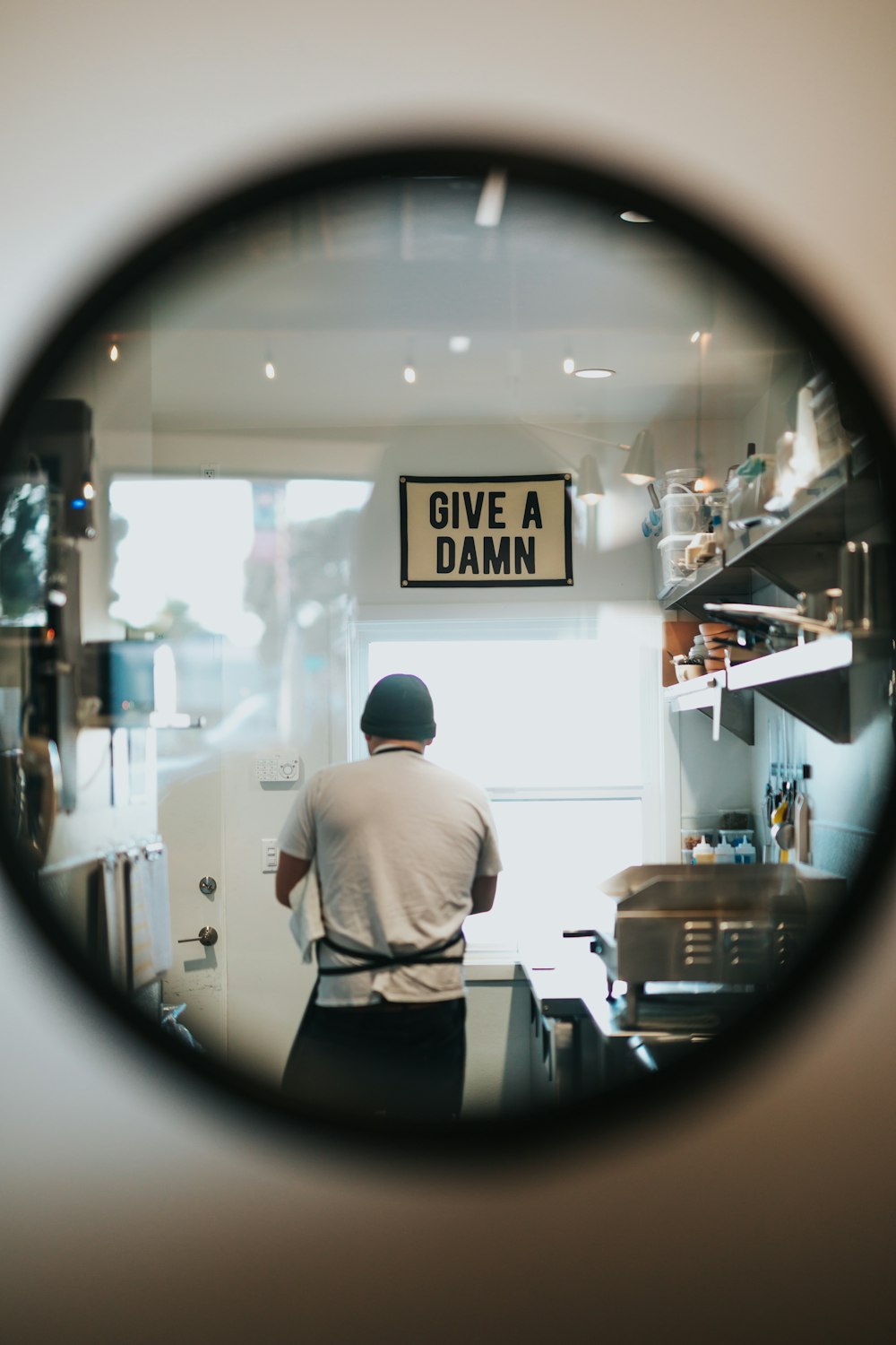 a man standing in a kitchen behind a magnifying glass