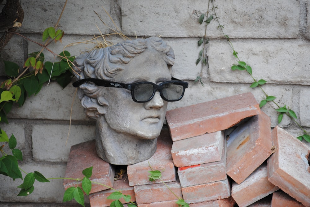 gray concrete head bust on brown brick wall