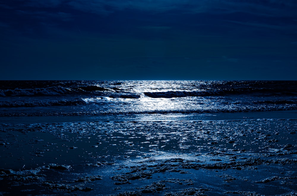 ocean waves crashing on shore during night time