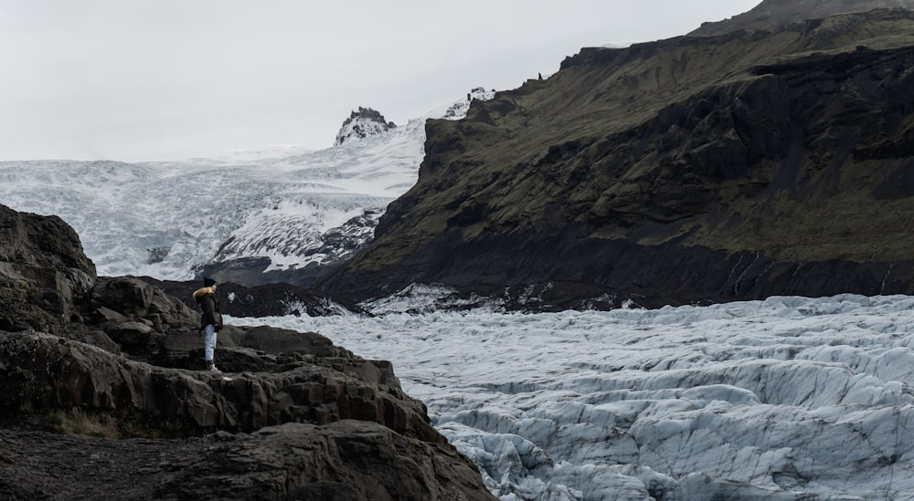 a man standing on top of a mountain next to a glacier