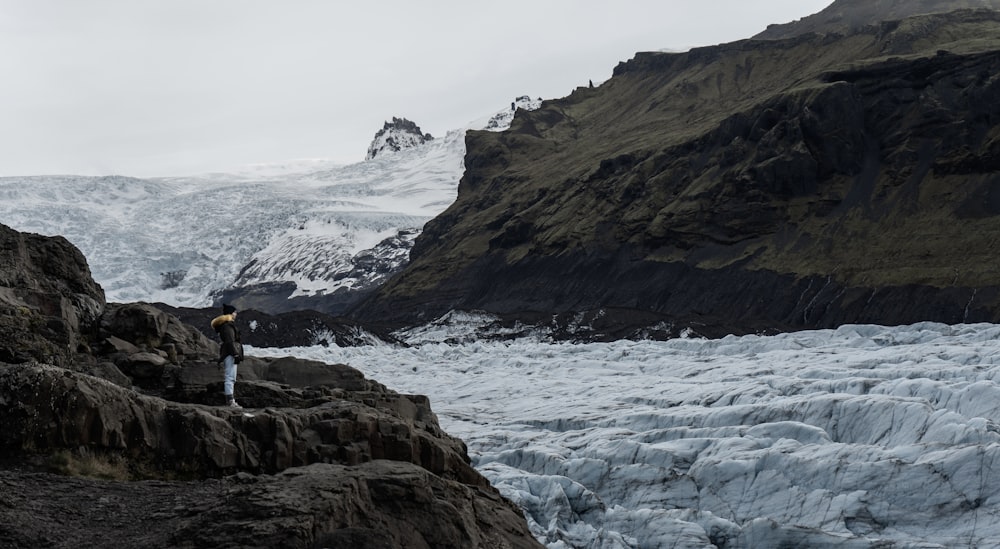 Un uomo in piedi sulla cima di una montagna vicino a un ghiacciaio