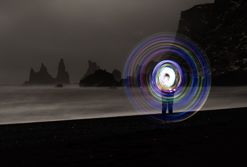 une personne debout sur une plage avec une peinture lumineuse