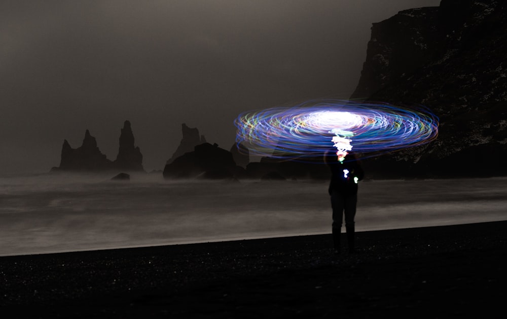 a man standing on top of a beach under a light painting