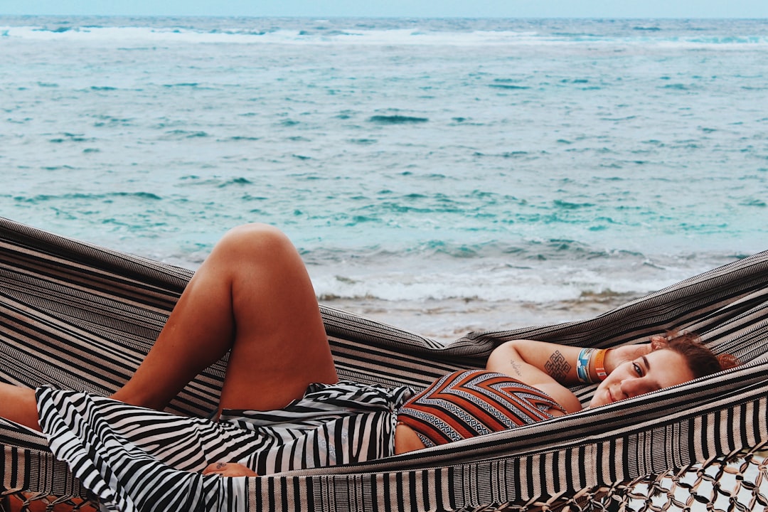 woman in black and white stripe dress lying on brown wooden beach lounge chair