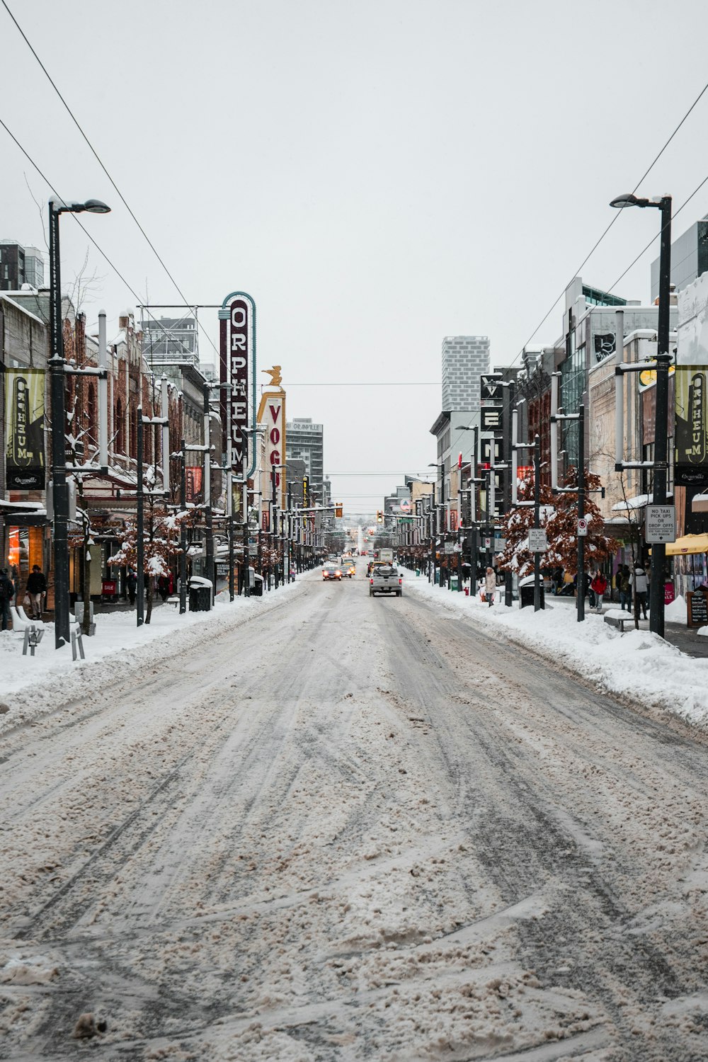 a snowy street with a car driving down it