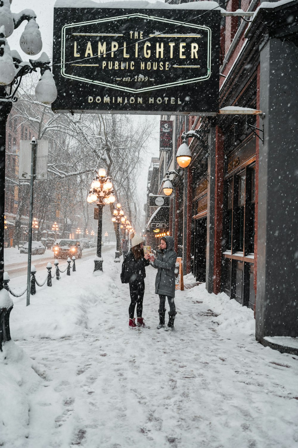 a couple of people walking down a snow covered street